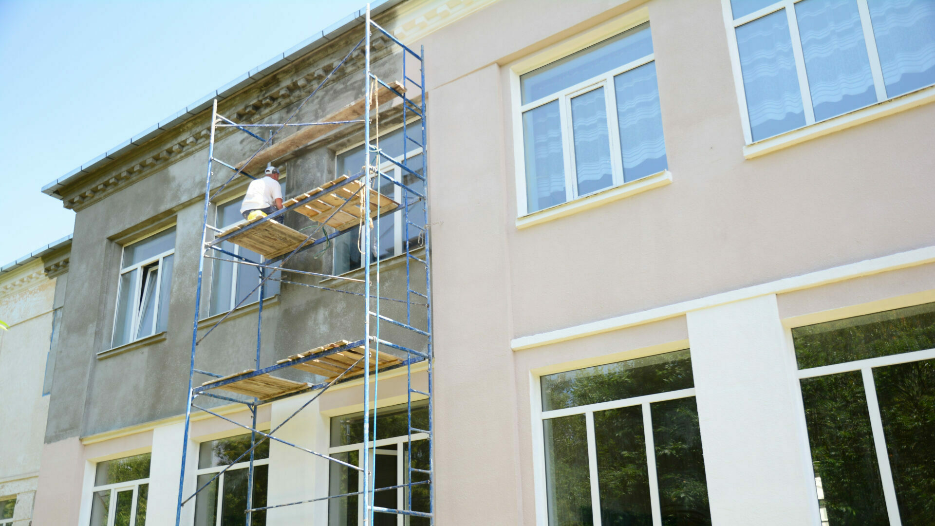 Builder contractor plastering external walls before painting outside house facade. Prepare for painting house exterior walls.